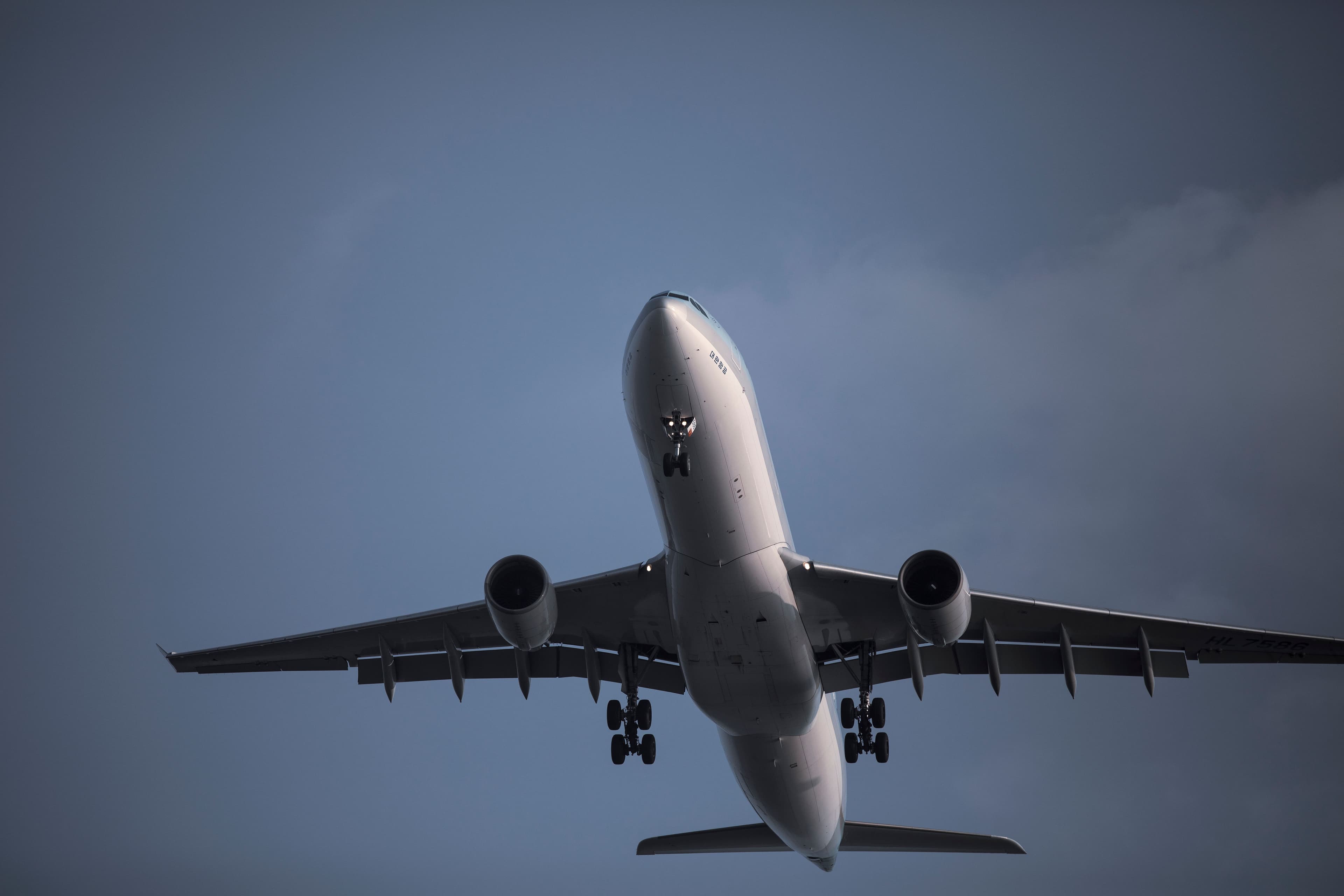 Avión de gran tamaño visto desde abajo en pleno vuelo, con el tren de aterrizaje desplegado