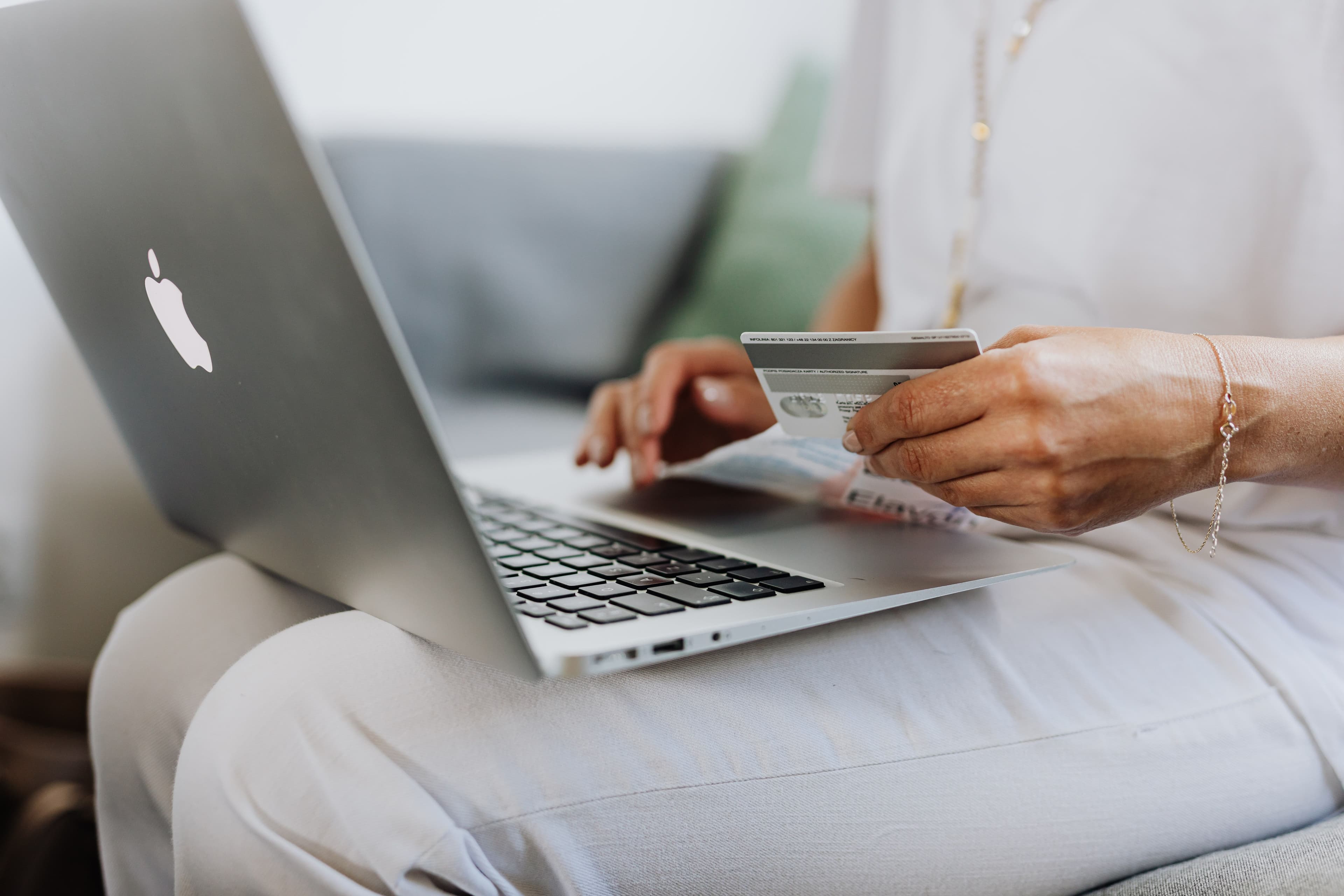 Persona comprando en línea con una tarjeta de crédito y un computador portátil